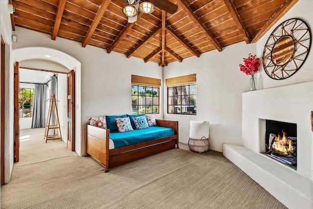 living area featuring light carpet, vaulted ceiling with beams, wood ceiling, and plenty of natural light