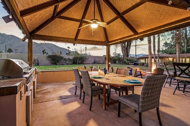 view of patio / terrace featuring ceiling fan, a gazebo, an outdoor kitchen, and a mountain view