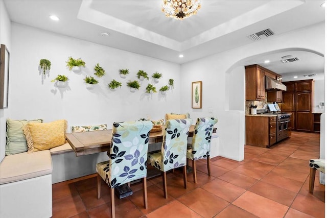 dining room with tile patterned flooring, a tray ceiling, and breakfast area