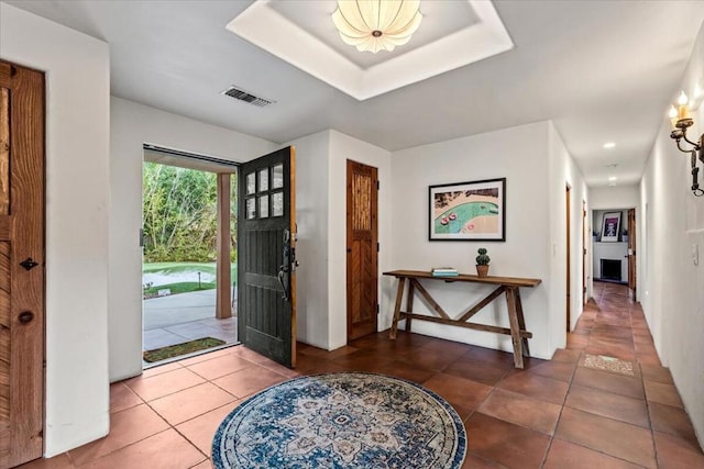 tiled entrance foyer featuring a raised ceiling