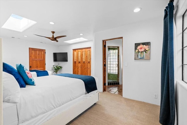 carpeted bedroom featuring ceiling fan, a closet, and a skylight