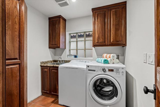 laundry area with light tile patterned flooring, sink, washing machine and clothes dryer, and cabinets