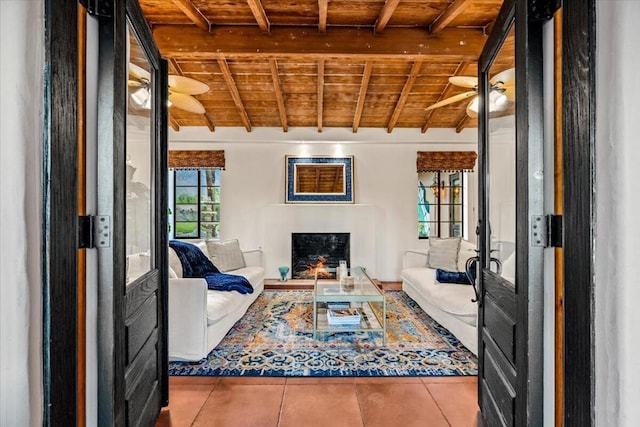 living room featuring ceiling fan, wooden ceiling, light tile patterned floors, and beamed ceiling