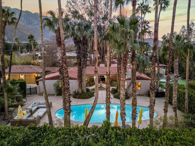 pool at dusk featuring a mountain view and a patio