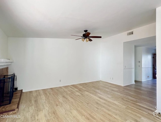 living room featuring ceiling fan, a tiled fireplace, and light wood-type flooring