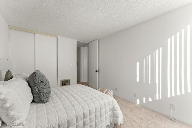 bedroom featuring a textured ceiling, a closet, and light colored carpet