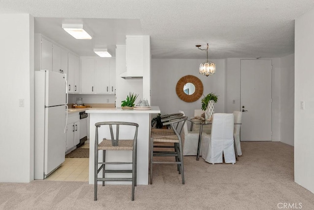 kitchen featuring pendant lighting, white cabinetry, light carpet, white fridge, and a kitchen breakfast bar