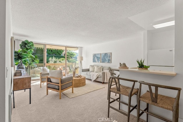 living room featuring a textured ceiling, a wall of windows, and light colored carpet