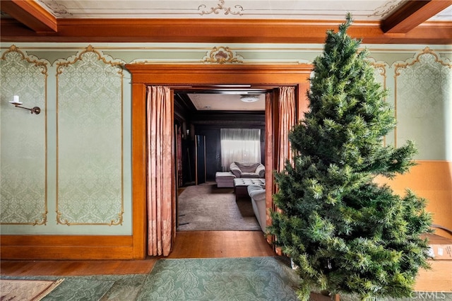 corridor featuring crown molding, wood-type flooring, and beamed ceiling