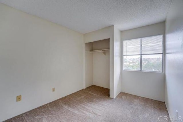 unfurnished bedroom with a textured ceiling, carpet floors, and a closet