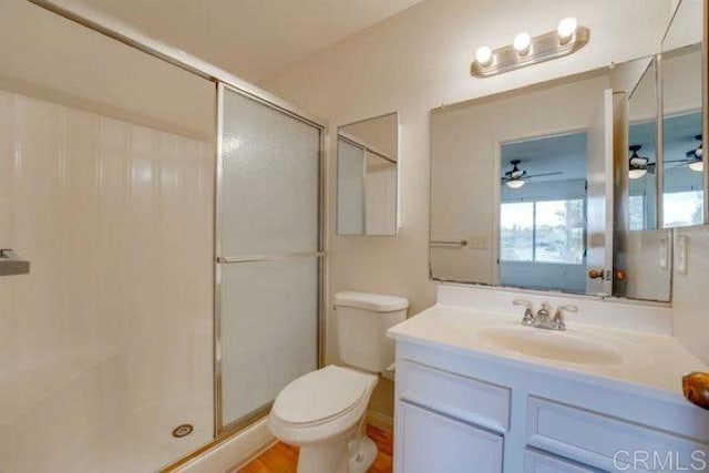 bathroom with ceiling fan, vanity, a shower with shower door, and toilet