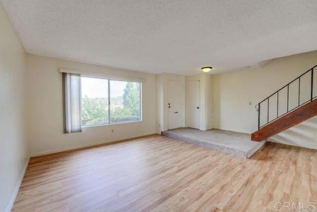 unfurnished living room featuring a textured ceiling and light hardwood / wood-style floors