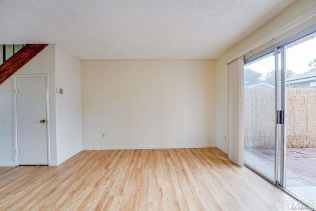 spare room with a textured ceiling and light hardwood / wood-style flooring