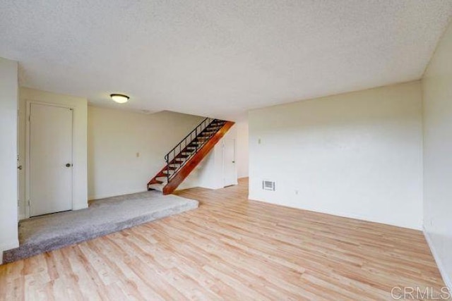 spare room with a textured ceiling and light hardwood / wood-style flooring