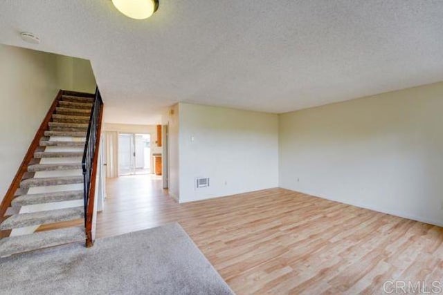 unfurnished room with a textured ceiling and light hardwood / wood-style flooring