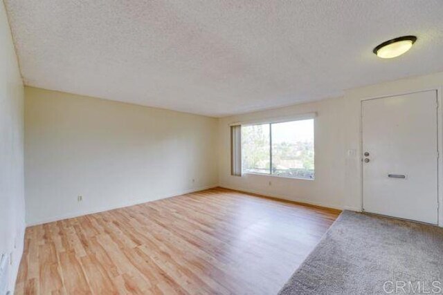 spare room with light wood-type flooring and a textured ceiling