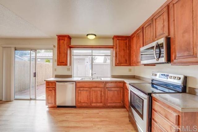 kitchen with appliances with stainless steel finishes, sink, and light wood-type flooring