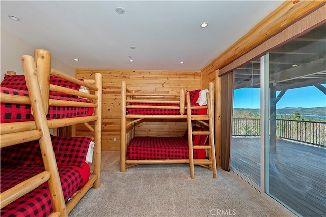 carpeted bedroom featuring access to outside, wooden walls, and a mountain view