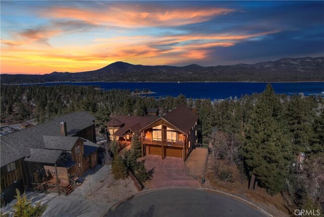 aerial view at dusk featuring a water and mountain view