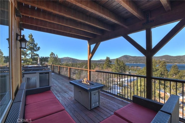 deck with a water and mountain view and an outdoor fire pit