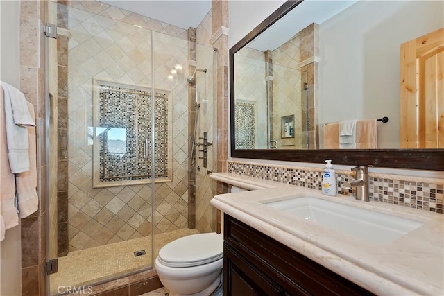 bathroom featuring toilet, a shower with shower door, backsplash, and vanity