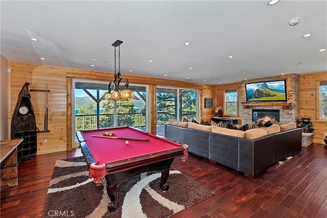 rec room with billiards, dark hardwood / wood-style floors, wood walls, and a stone fireplace