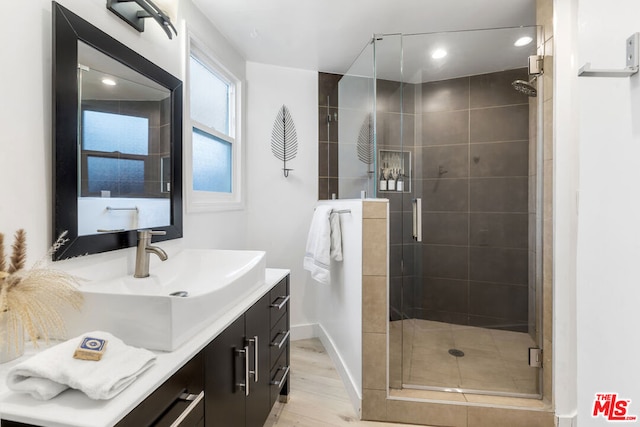 bathroom featuring hardwood / wood-style flooring, vanity, and a shower with door