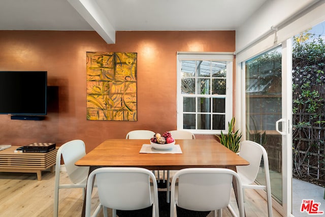 dining space with beamed ceiling and light hardwood / wood-style flooring