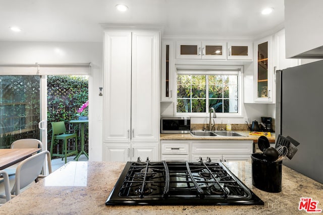 kitchen featuring black gas cooktop, sink, white cabinetry, a healthy amount of sunlight, and light stone counters