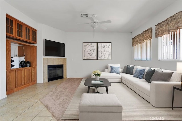 living room featuring ceiling fan, light tile patterned floors, and a tiled fireplace