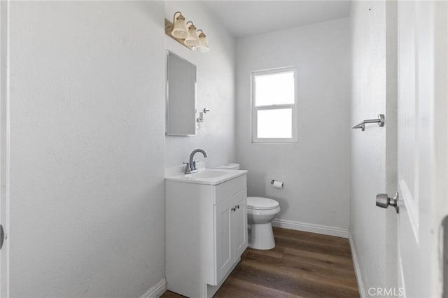 bathroom featuring wood-type flooring, toilet, and vanity