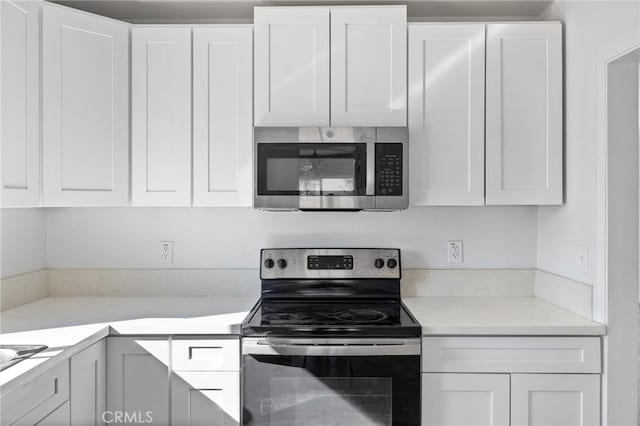 kitchen with light stone countertops, appliances with stainless steel finishes, and white cabinetry