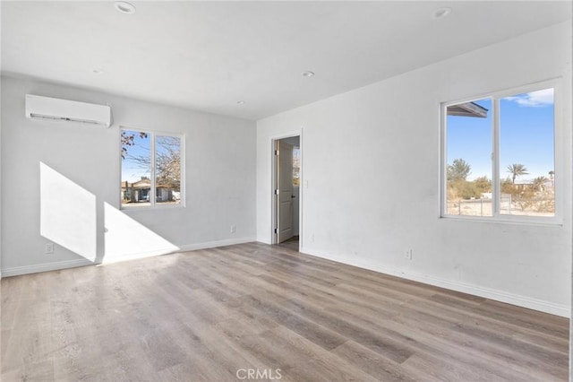 empty room with light wood-type flooring and a wall mounted AC