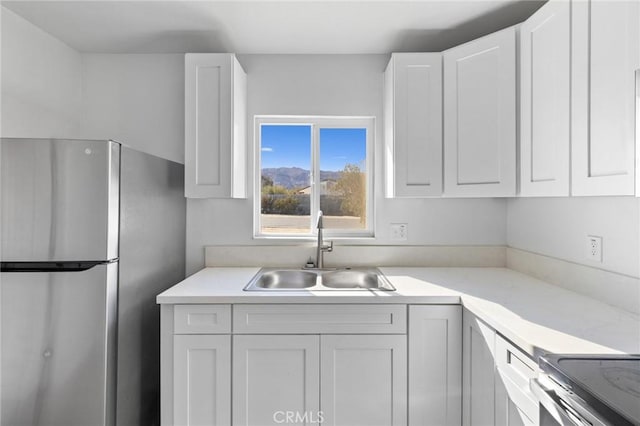 kitchen featuring white cabinets, stainless steel fridge, and sink