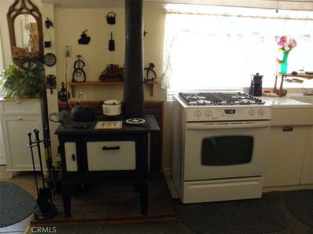 kitchen featuring a wood stove, white cabinetry, and white gas range