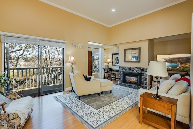 living room featuring a tile fireplace, crown molding, and hardwood / wood-style flooring