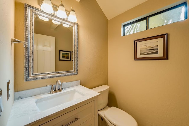 bathroom with lofted ceiling, vanity, and toilet