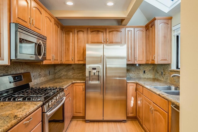 kitchen featuring decorative backsplash, sink, light stone counters, and stainless steel appliances