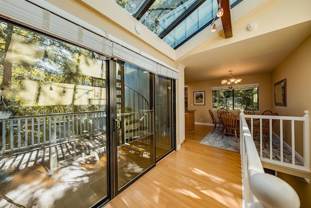 doorway featuring a chandelier, hardwood / wood-style floors, and vaulted ceiling with skylight