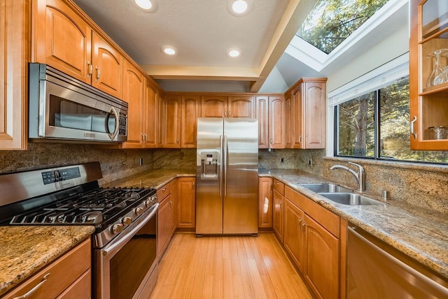 kitchen featuring light stone countertops, appliances with stainless steel finishes, a wealth of natural light, and sink