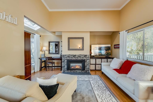 living room featuring a skylight, crown molding, hardwood / wood-style floors, and a tile fireplace