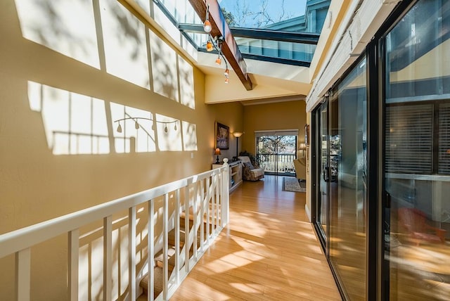 hall with high vaulted ceiling, hardwood / wood-style flooring, a skylight, and beamed ceiling