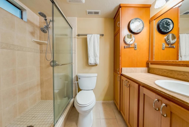 bathroom featuring toilet, tile patterned flooring, a shower with door, and vanity