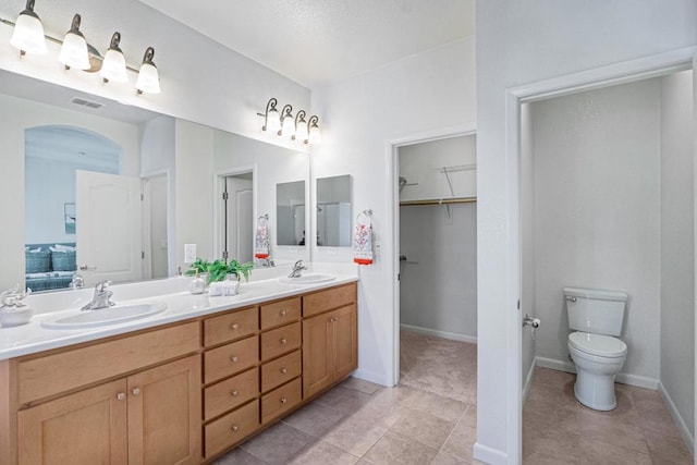 bathroom with toilet, vanity, and tile patterned flooring