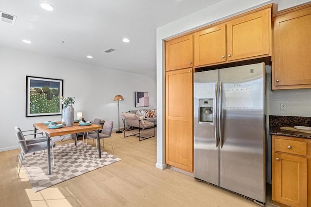 kitchen featuring light hardwood / wood-style flooring, stainless steel fridge with ice dispenser, and dark stone countertops