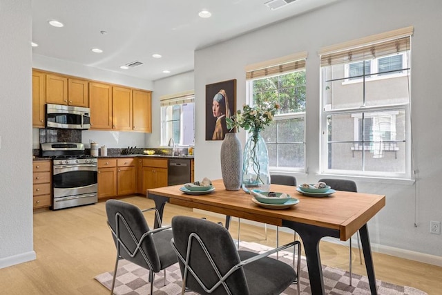 kitchen with appliances with stainless steel finishes, light hardwood / wood-style flooring, tasteful backsplash, and sink