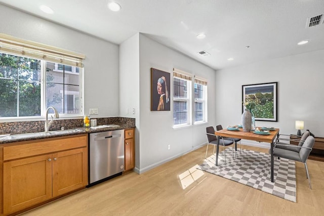 interior space with dark stone countertops, sink, stainless steel dishwasher, and light wood-type flooring