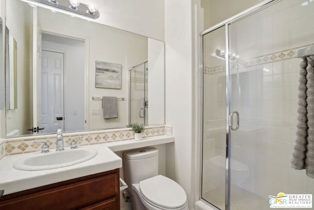 bathroom featuring toilet, an enclosed shower, and vanity