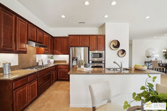 kitchen featuring a center island, light tile patterned floors, stone countertops, appliances with stainless steel finishes, and sink