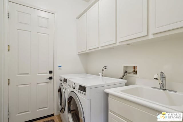 laundry area featuring sink, washing machine and clothes dryer, and cabinets